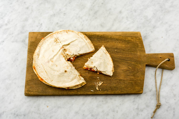 Snijd het gevulde platbrood in punten en verdeel over de borden.