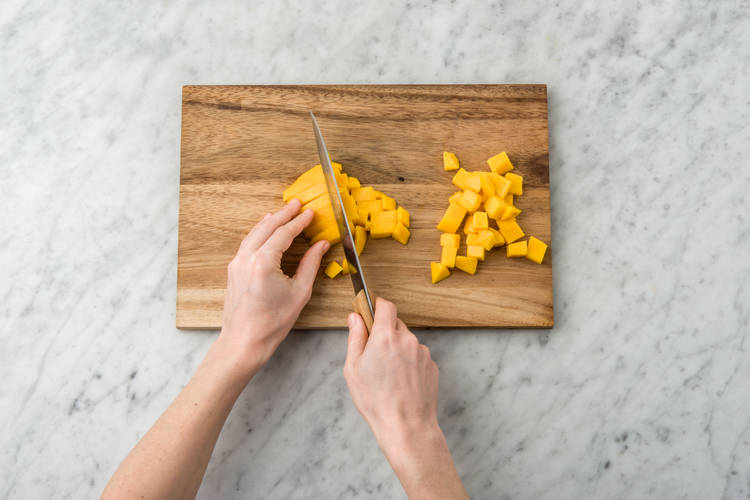 Schil ondertussen de mango en snijd het vruchtvlees klein.