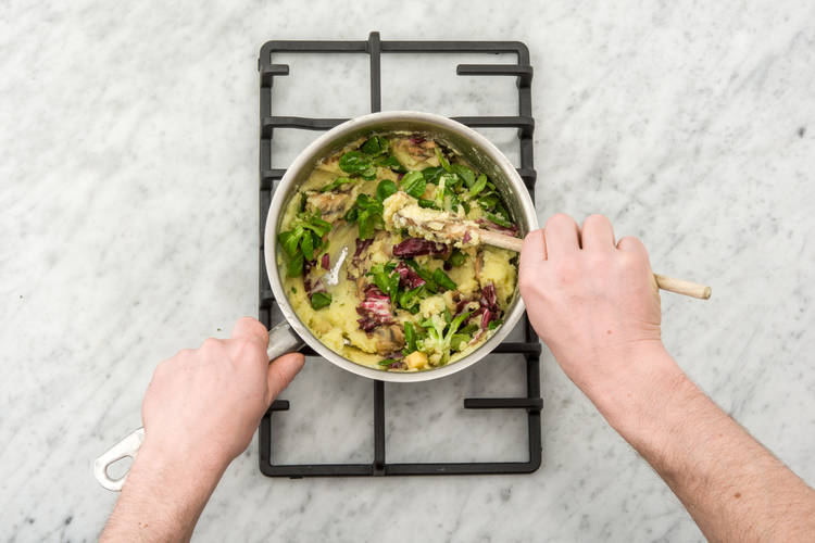 Roer de veldsla-raddichiomelange, de kruidenkaasblokjes en de champignons door de stamppot.