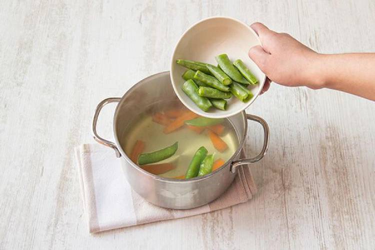 Cook the carrots and snap peas.