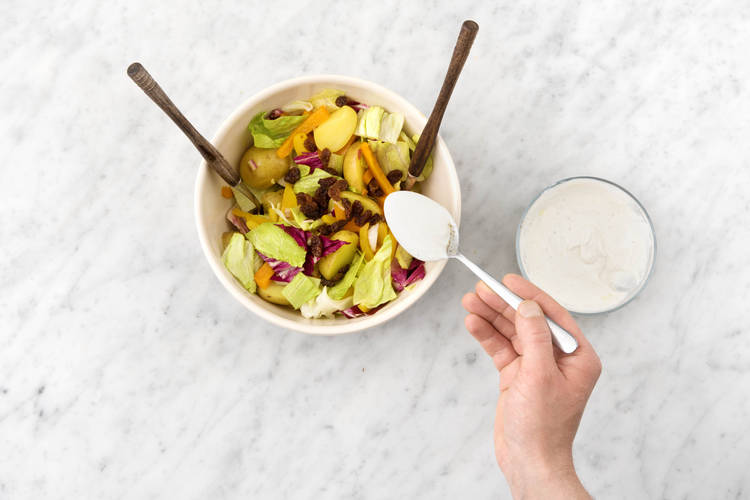 Voeg de dressing toe aan de salade.