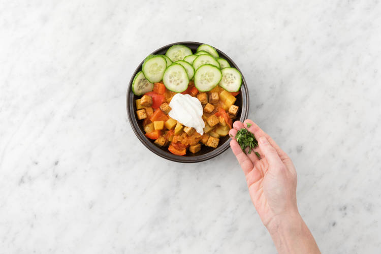 Serveer met de komkommer en garneer met de koriander en overige yoghurt