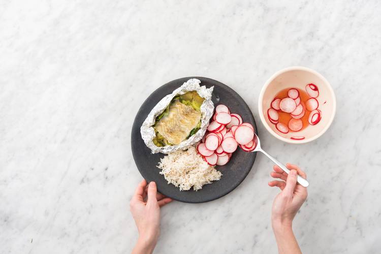 Servir le riz au sésame et les papillotes de poisson sur les assiettes et accompagner des radis aigres-doux.