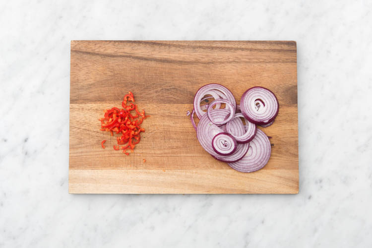 Snijd de rode ui in halve ringen en verwijder de zaadlijsten van de rode peper en snijd de rode peper fijn.