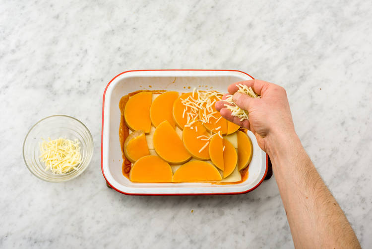 Recouvrez-la de feuilles de lasagne et appuyez fermement. Disposez une partie de la courge sur les feuilles de lasagne et parsemez avec ¼ du chèvre.