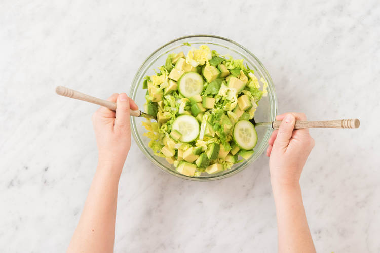 Salatstreifen, Gurkenscheiben und Avocadowürfel unterheben