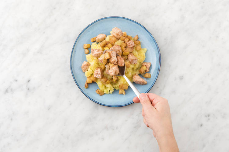 Schep de gebakken kipfiletstukjes met appel op de puree.