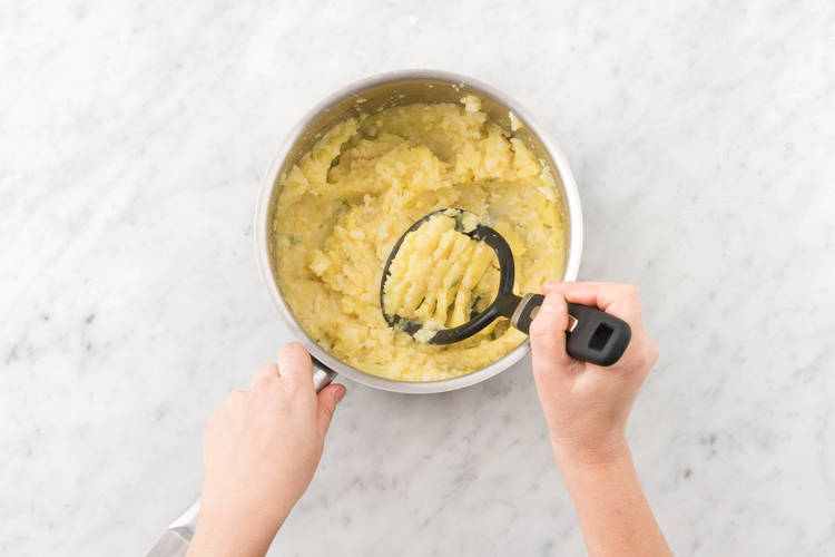 Stamp de aardappelen, knolselderij en tijm tot een grove puree met een aardappelstamper.