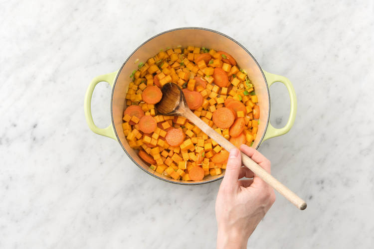 Bak de knoflook, peen, pompoenblokjes, currykruiden en overige bosui in een soeppan.
