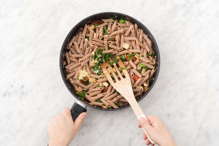 Voeg vervolgens de penne, 1 el kookvocht per persoon en de helft van de grana padano toe aan de groenten.