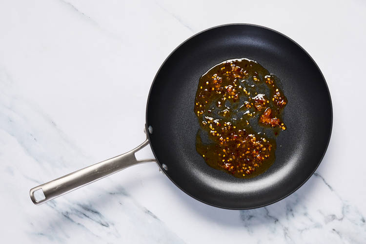 Griller les noix de Grenoble et préparer la sauce piquante au miel et à l’orange