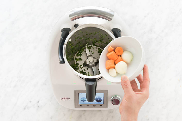 Zwiebelhälften, Knoblauch und Karottenstücke zerkleinern.