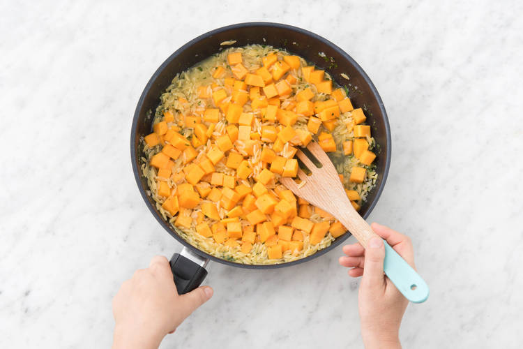 Schep de pompoenblokjes door de orzo