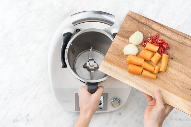 Zwiebelhälften, grobe Karottenstücke, grobe Chiliringe und Knoblauch in den Mixtopf geben