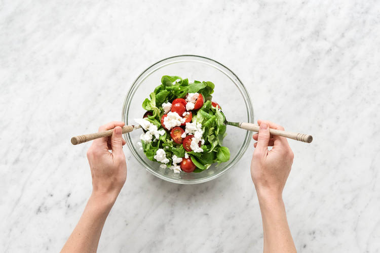 Feldsalat und die Kirschtomatenhälften hineingeben und vermengen
