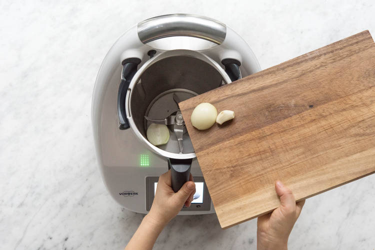 Zwiebelhälften und Knoblauch in den Mixtopf geben