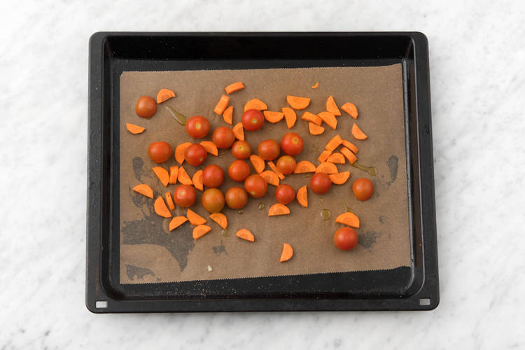 Verdeel de tomaten en peen in een ovenschaal