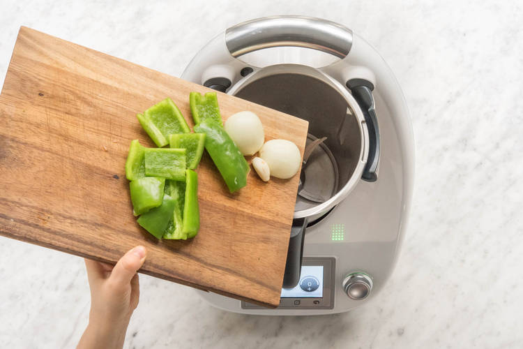 Knoblauch, Zwiebelhälften und grobe Paprikastücke in den Mixtopf geben