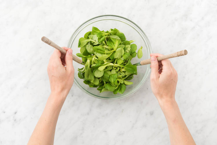 Feldsalat mit dem Dressing vermischen