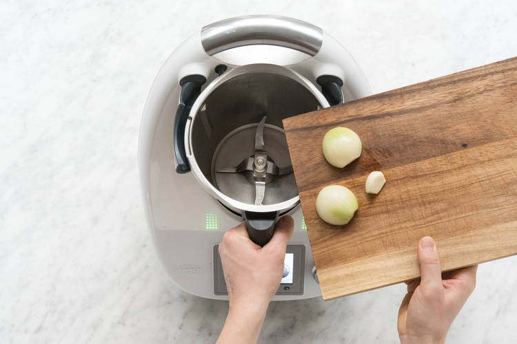 Zwiebelhälften und Knoblauch in den Mixtopf geben