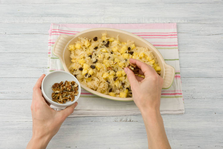 Schep de zuurkool in de ovenschaal en bestrooi met de oude kaas en pecannoten