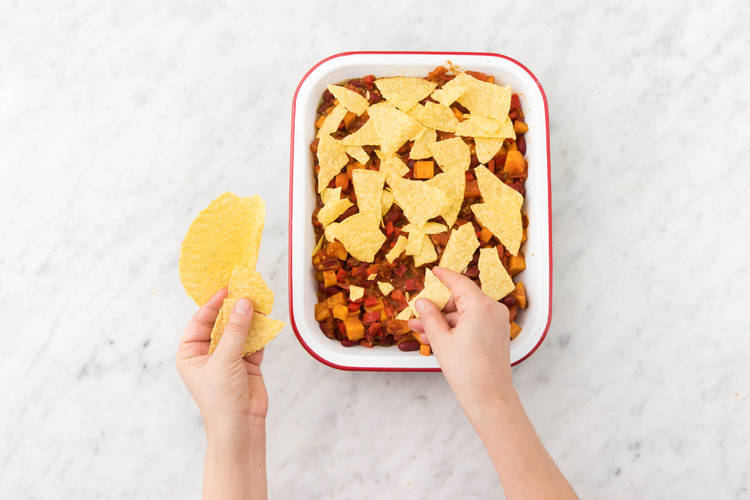 Verkruimel de tacoschelpen erover en bestrooi met de cheddar