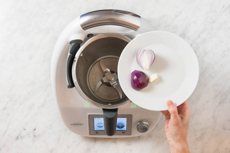 Knoblauch und Zwiebelhälften in den Mixtopf geben