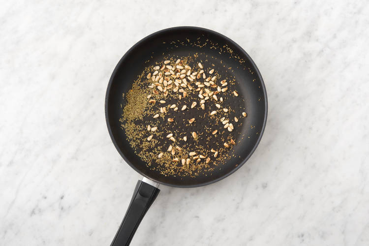 Rooster de pijnboompitten met de rozemarijn