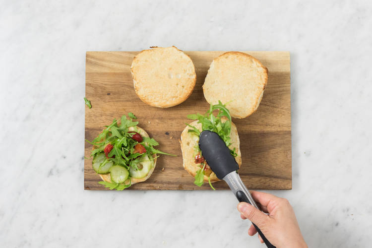 Rucola-Antipasti-Mischung auf die Unterseiten der Brötchenhälften verteilen,