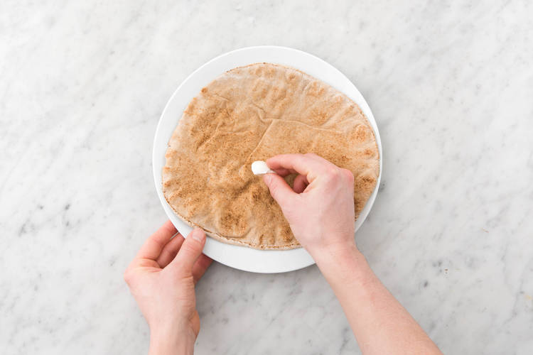 Wrijf het volkoren platbrood in met de knoflook en bak in 3 - 5 minuten in de oven