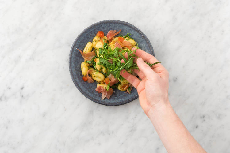 Verdeel de gnocchi over de borden en garneer met de serranoham en overige rucola