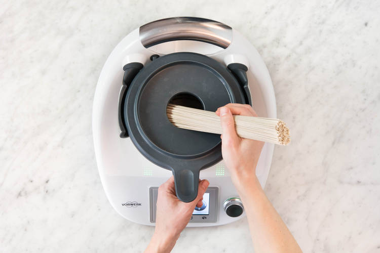 Soba-Nudeln durch die Deckelöffnung in den Mixtopf geben